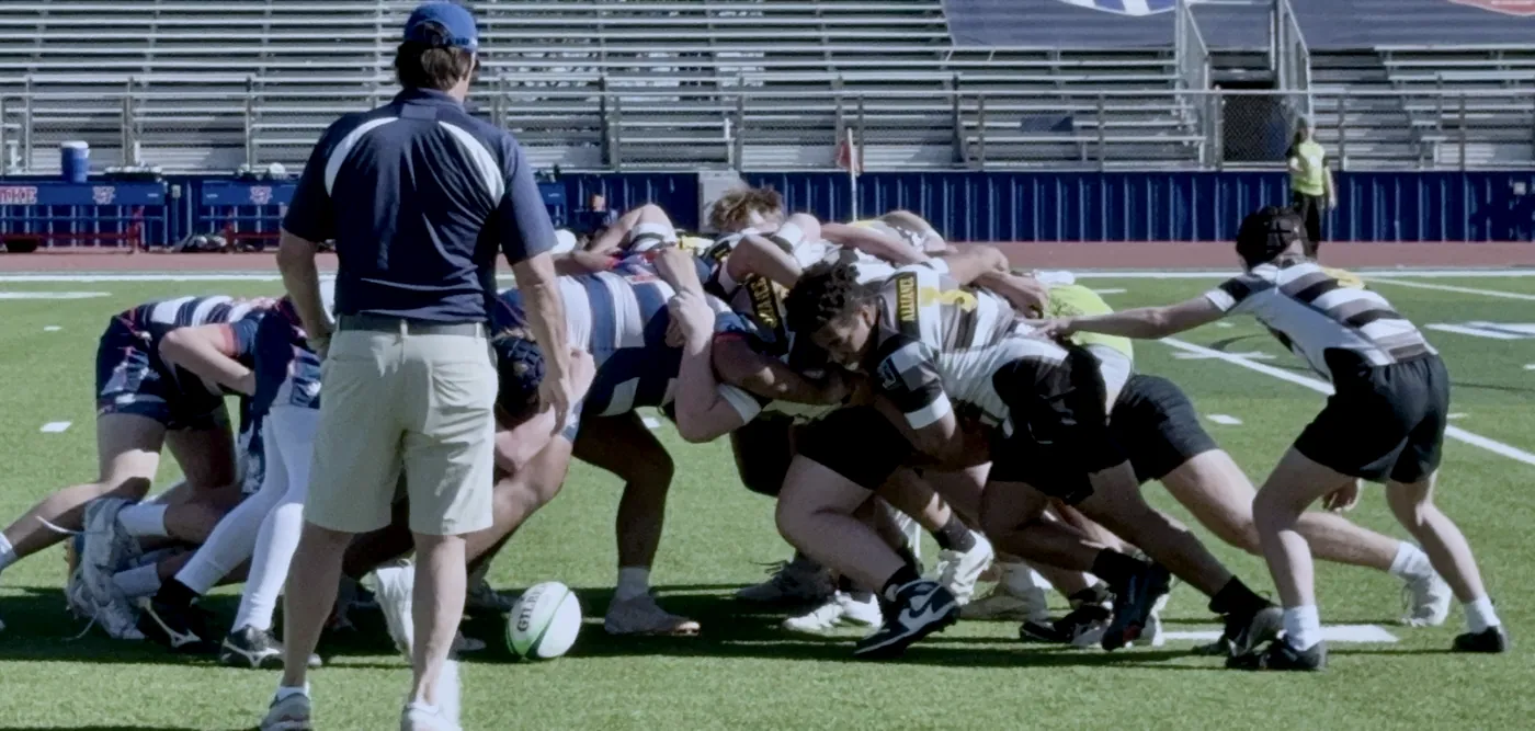 Black Knights players set a scrum while a coach watches